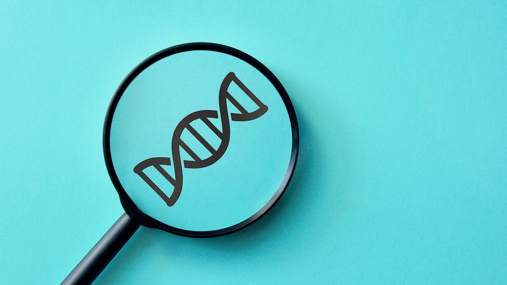 Lente d'ingrandimento su un simbolo di DNA su sfondo turchese, concetto di nutrigetica e nutrigenomica e ricerca scientifica.